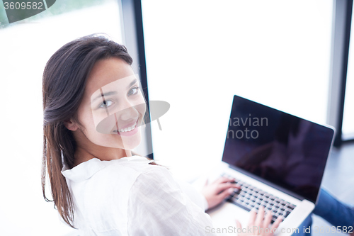 Image of relaxed young woman at home working on laptop computer