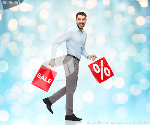 Image of smiling man walking with red shopping bag