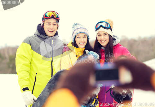 Image of happy friends with snowboards and smartphone