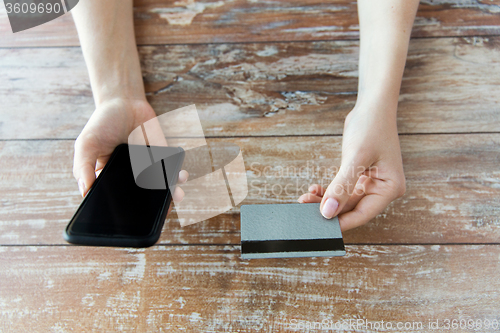 Image of close up of hands with smart phone and credit card