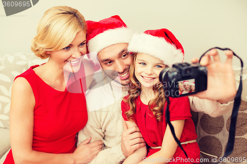 Image of smiling family in santa helper hats taking picture