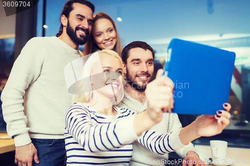 Image of happy friends with tablet pc taking selfie at cafe