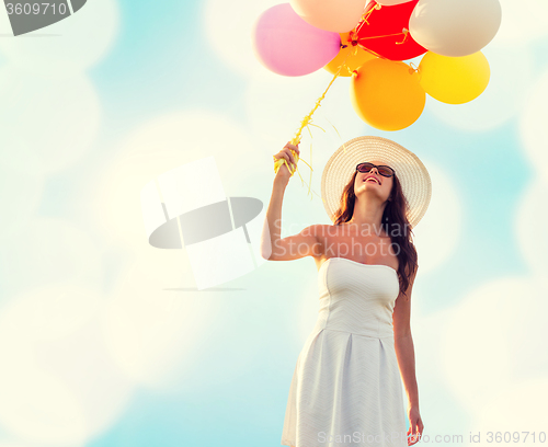 Image of smiling young woman in sunglasses with balloons