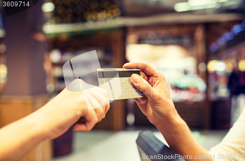 Image of close up of hands giving credit card in mall