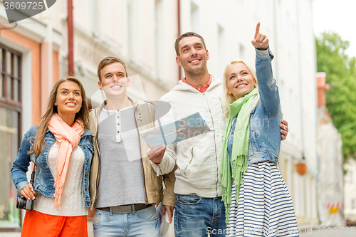 Image of group of smiling friends with map and photocamera