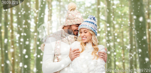 Image of happy couple in winter clothes hugging over forest