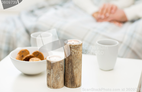 Image of close up of candles, cookies and tea cups on table