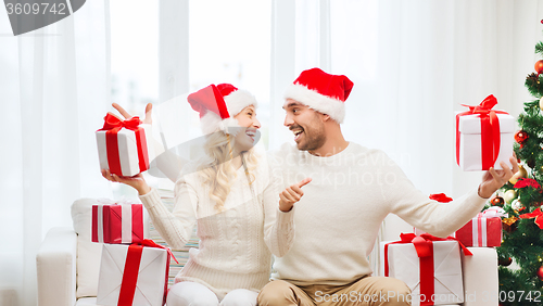 Image of happy couple with christmas gifts and thumbs up