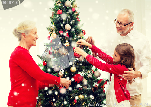 Image of smiling family decorating christmas tree at home