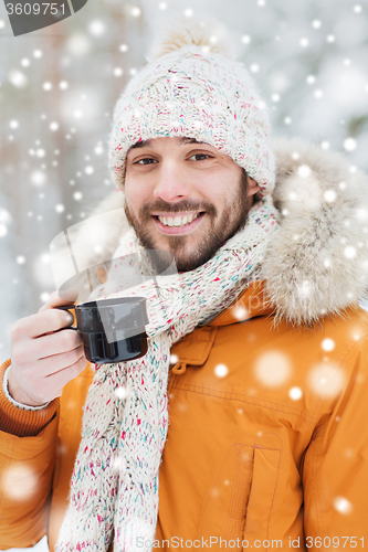 Image of smiling young man with cup in winter forest