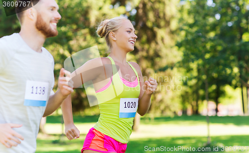 Image of happy sportsmen couple racing wit badge numbers