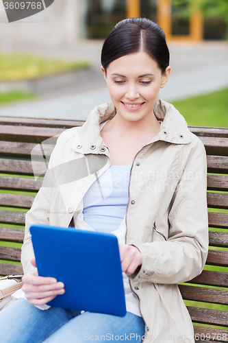 Image of woman with tablet pc sitting on bench in park