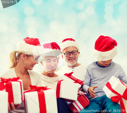 Image of happy family in santa helper hats with gift boxes