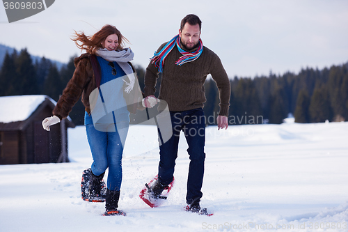 Image of couple having fun and walking in snow shoes