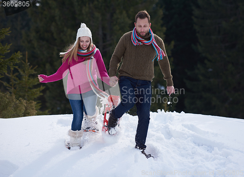 Image of couple having fun and walking in snow shoes