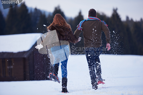 Image of couple having fun and walking in snow shoes