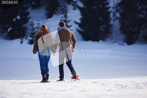 Image of couple having fun and walking in snow shoes