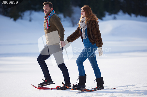 Image of couple having fun and walking in snow shoes