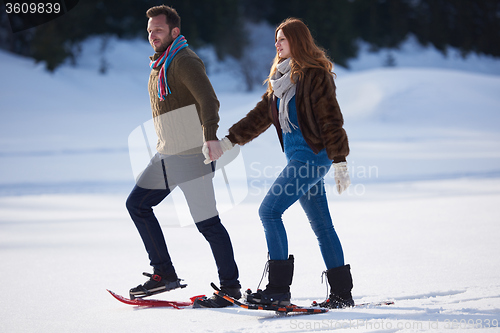 Image of couple having fun and walking in snow shoes