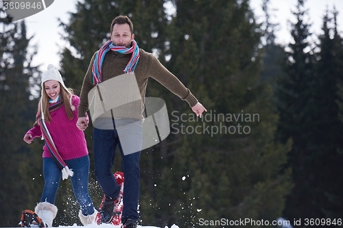 Image of couple having fun and walking in snow shoes