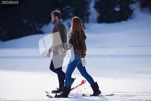 Image of couple having fun and walking in snow shoes