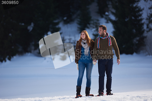 Image of couple having fun and walking in snow shoes