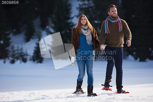 Image of couple having fun and walking in snow shoes