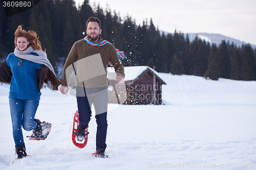 Image of couple having fun and walking in snow shoes