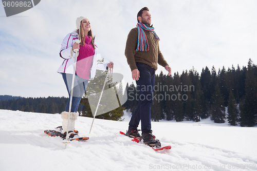 Image of couple having fun and walking in snow shoes