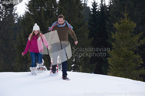 Image of couple having fun and walking in snow shoes