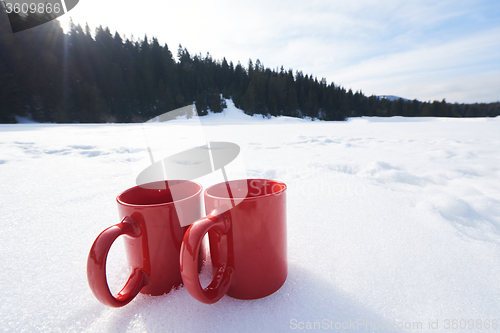 Image of two red coups of hot tea drink in snow  at winter