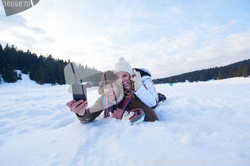 Image of romantic couple have fun in fresh snow and taking selfie