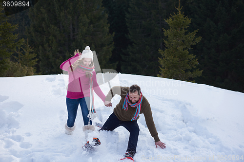 Image of couple having fun and walking in snow shoes
