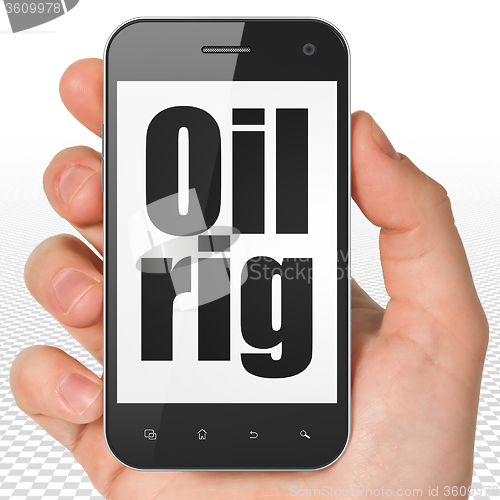 Image of Manufacuring concept: Hand Holding Smartphone with Oil Rig on display