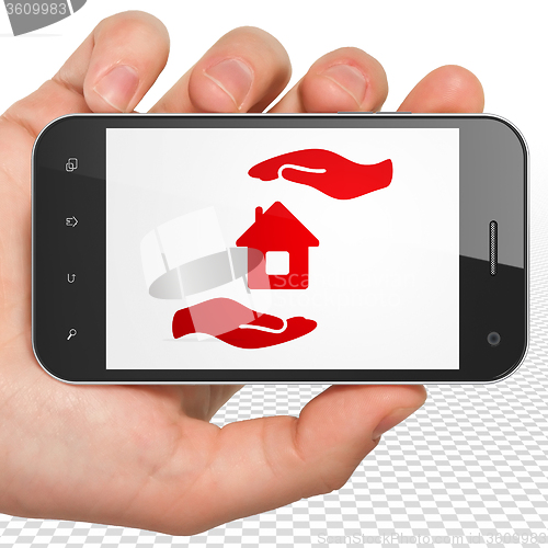 Image of Insurance concept: Hand Holding Smartphone with House And Palm on display