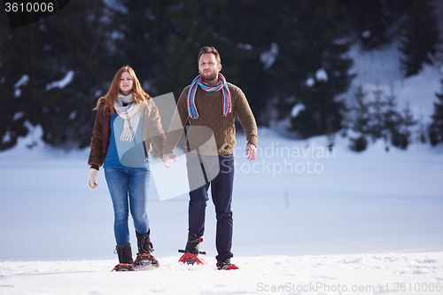 Image of couple having fun and walking in snow shoes