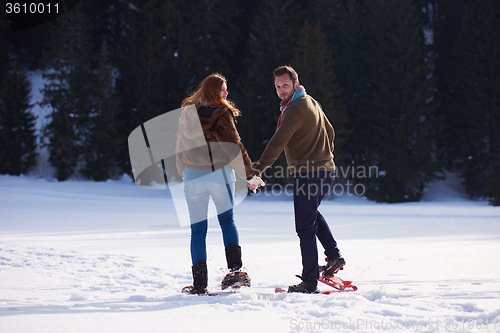 Image of couple having fun and walking in snow shoes