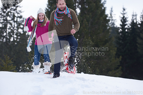 Image of couple having fun and walking in snow shoes