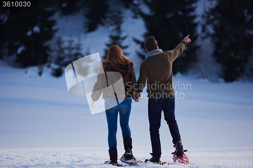 Image of couple having fun and walking in snow shoes