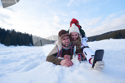 Image of romantic couple have fun in fresh snow and taking selfie