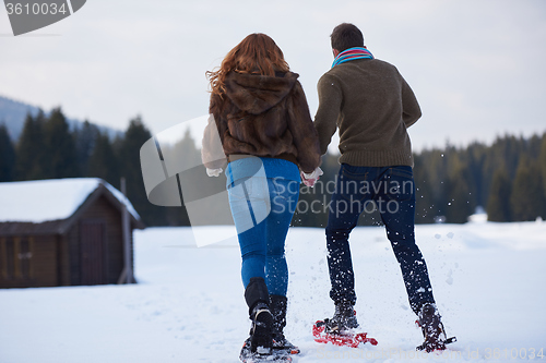 Image of couple having fun and walking in snow shoes