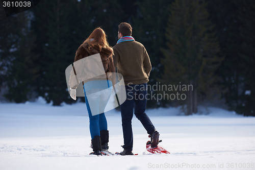 Image of couple having fun and walking in snow shoes