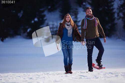 Image of couple having fun and walking in snow shoes