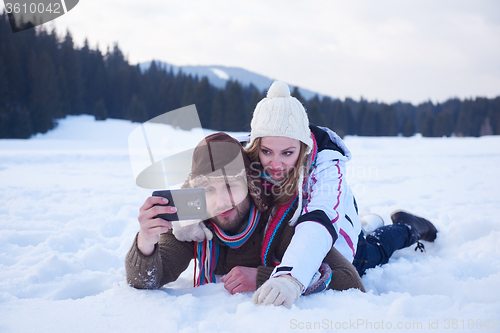 Image of romantic couple have fun in fresh snow and taking selfie