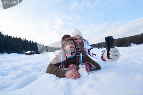 Image of romantic couple have fun in fresh snow and taking selfie
