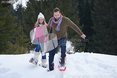 Image of couple having fun and walking in snow shoes