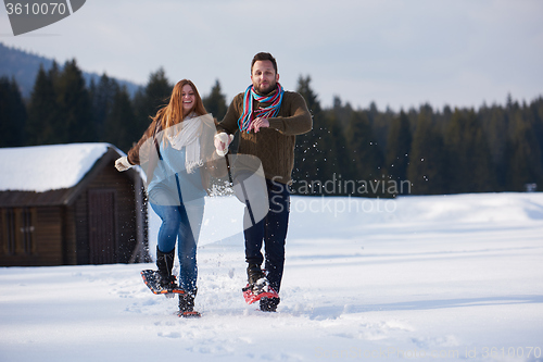 Image of couple having fun and walking in snow shoes