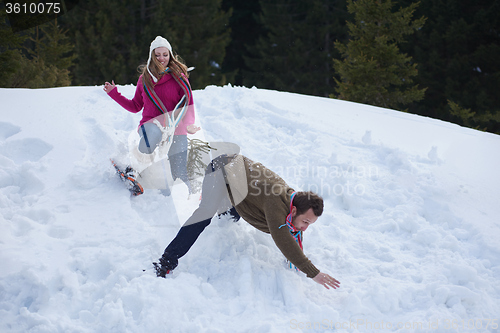 Image of couple having fun and walking in snow shoes