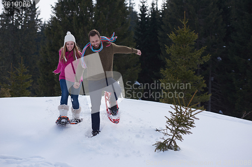Image of couple having fun and walking in snow shoes