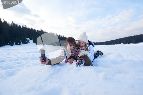 Image of romantic couple have fun in fresh snow and taking selfie